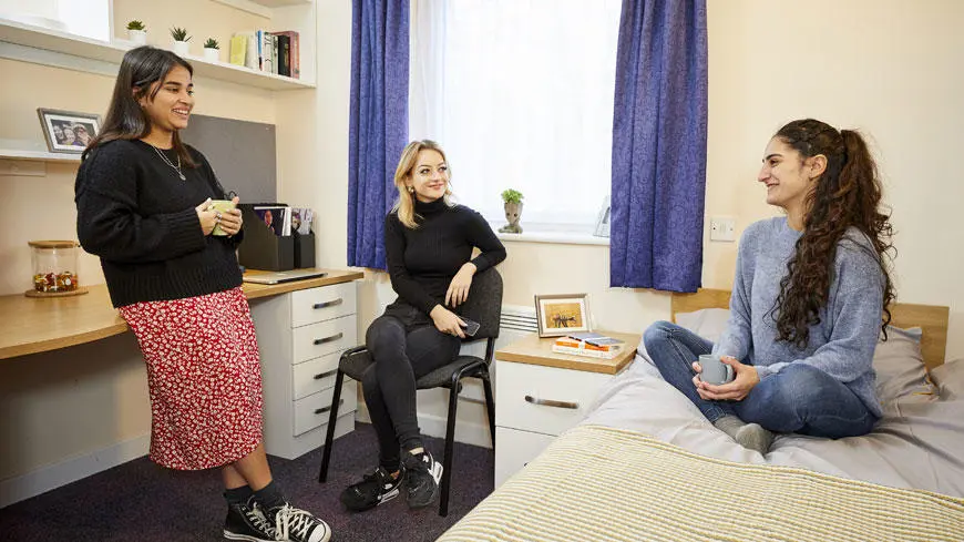 Three female students talking in a room in student accommodation