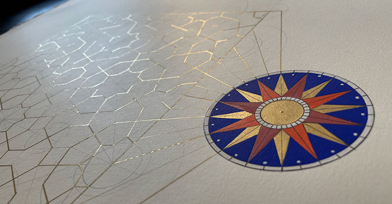 A drawing of a golden sun on a blue background with gold geometric lines