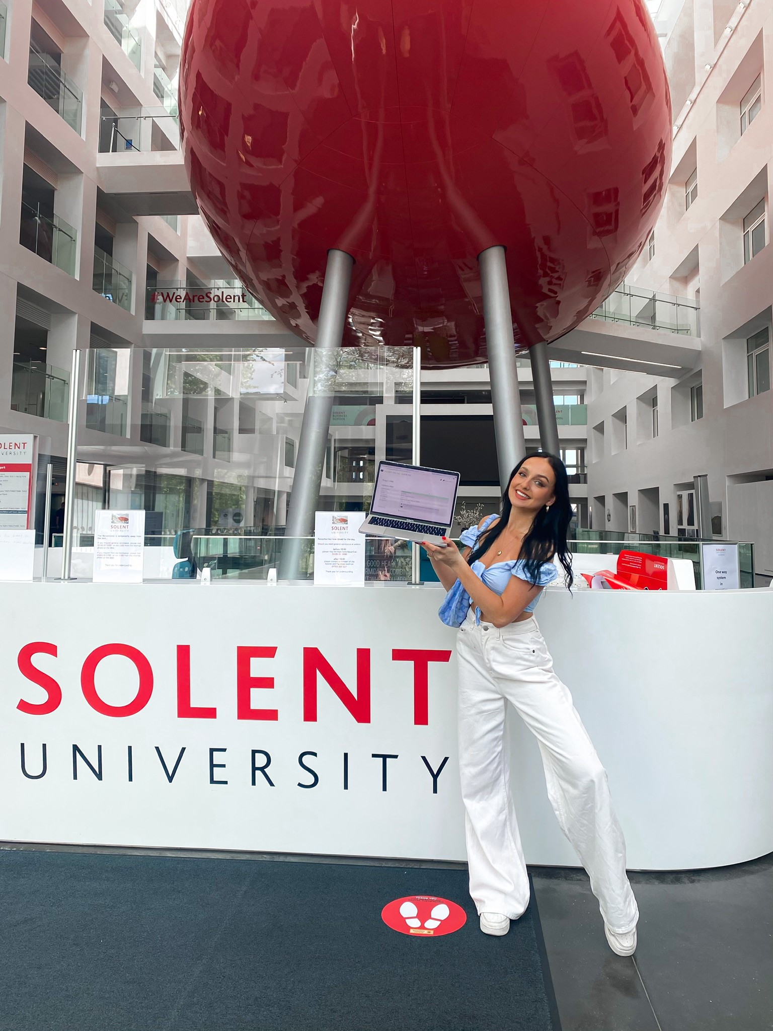 Image shows final year student Natasha Hughes holding a laptop in Solent's spark building