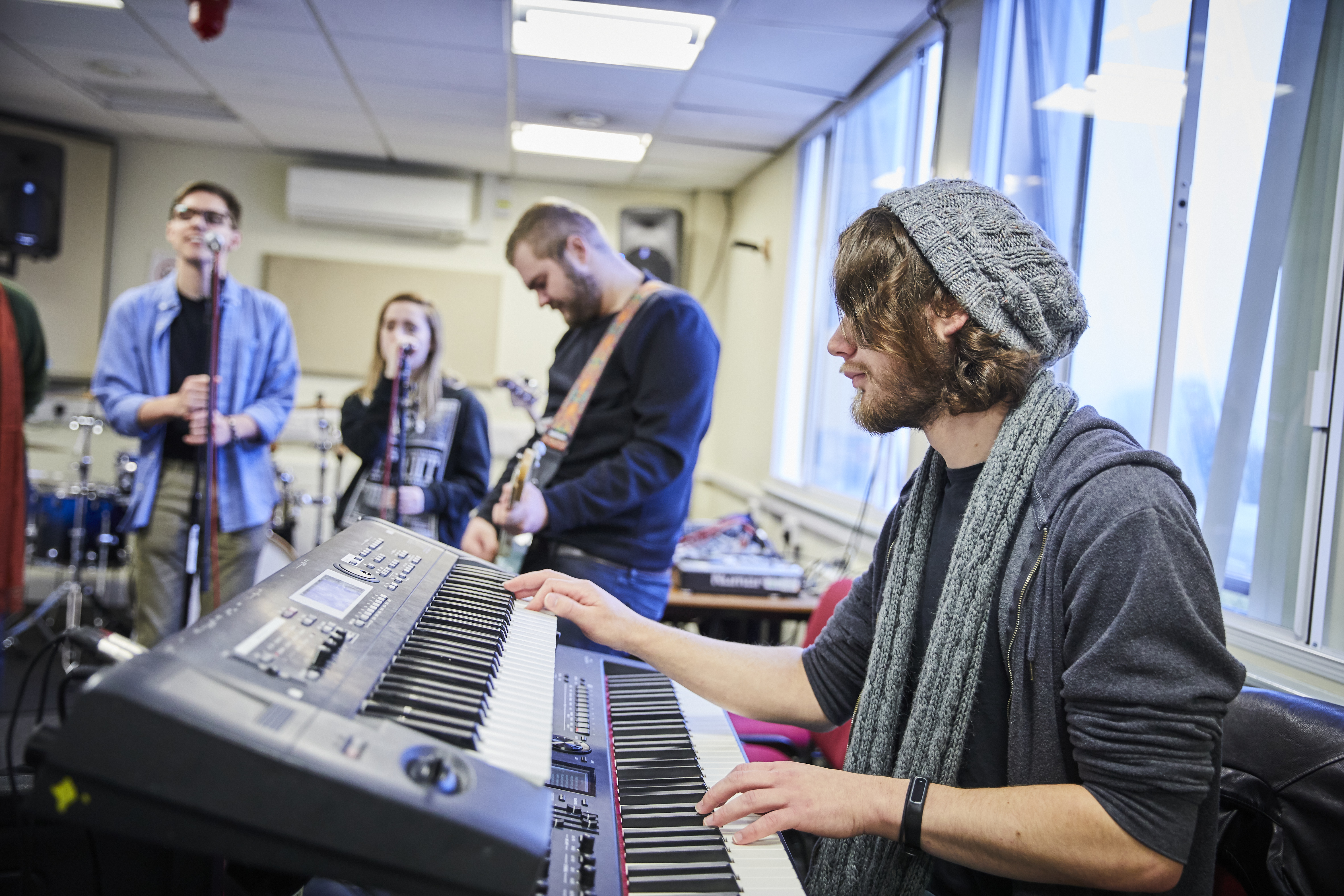 Picture of Solent students playing instruments together, keyboard, guitar and singing 