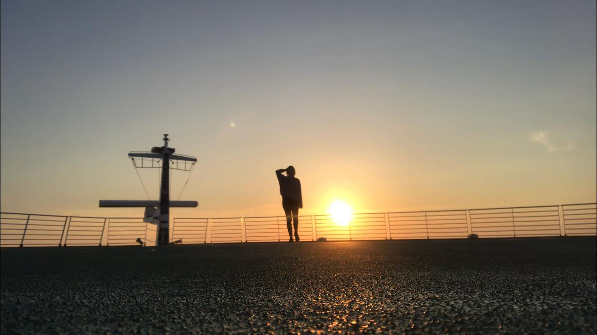 The silhouette of Alice Stansfield on a cruise liner behind a sunset
