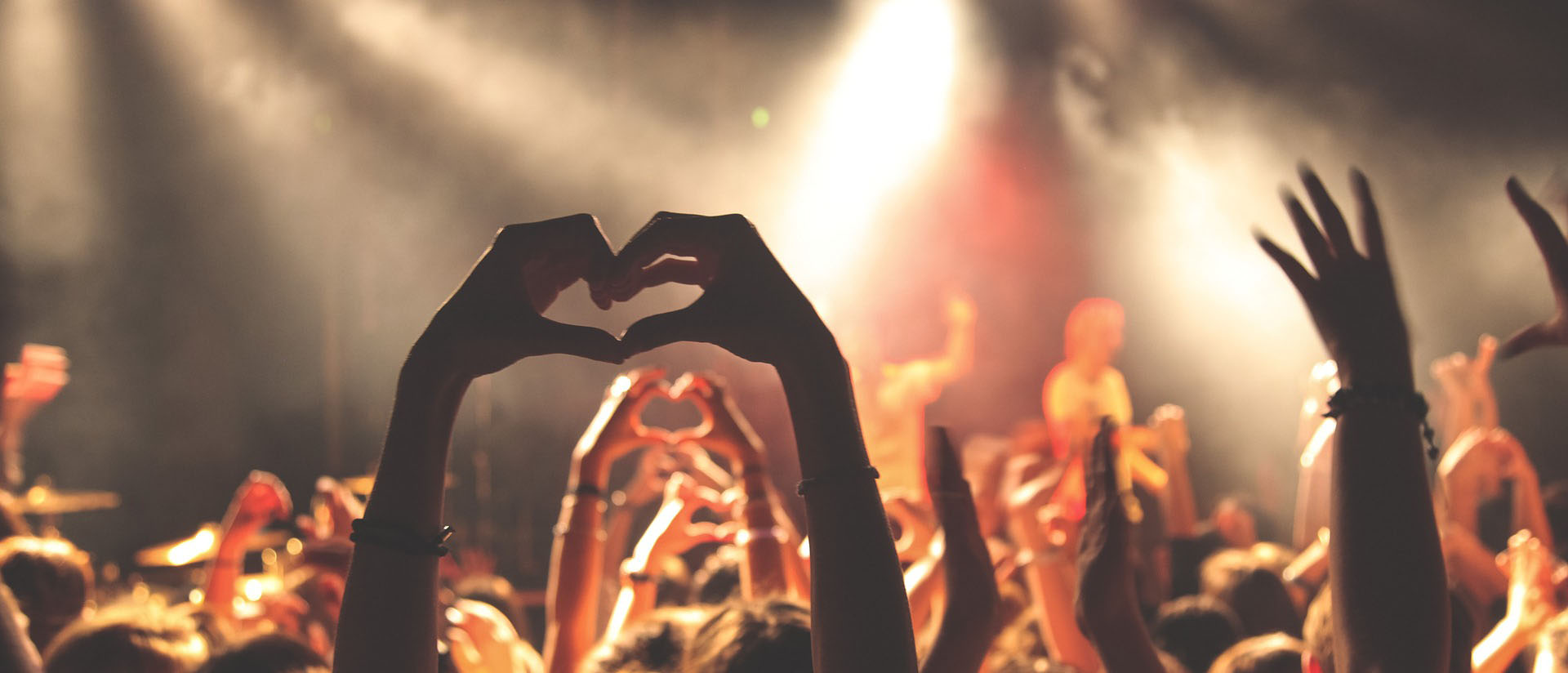 Gig goers making a heart symbol with their hands