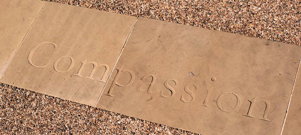 Patio area at broadmoore hospital with the word compassion carved in to the stone. Image credit: https://www.westlondon.nhs.uk/about-west-london-nhs-trust/sites-and-locations/broadmoor-hospital/
