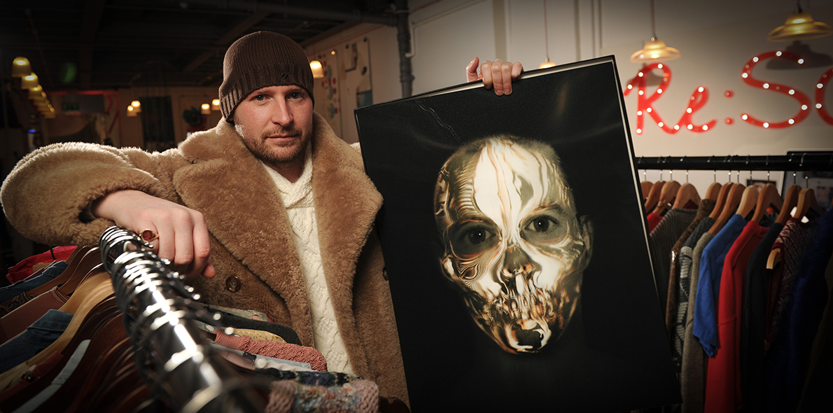 Gary James McQueen holding a piece of artwork in the Re:So shop