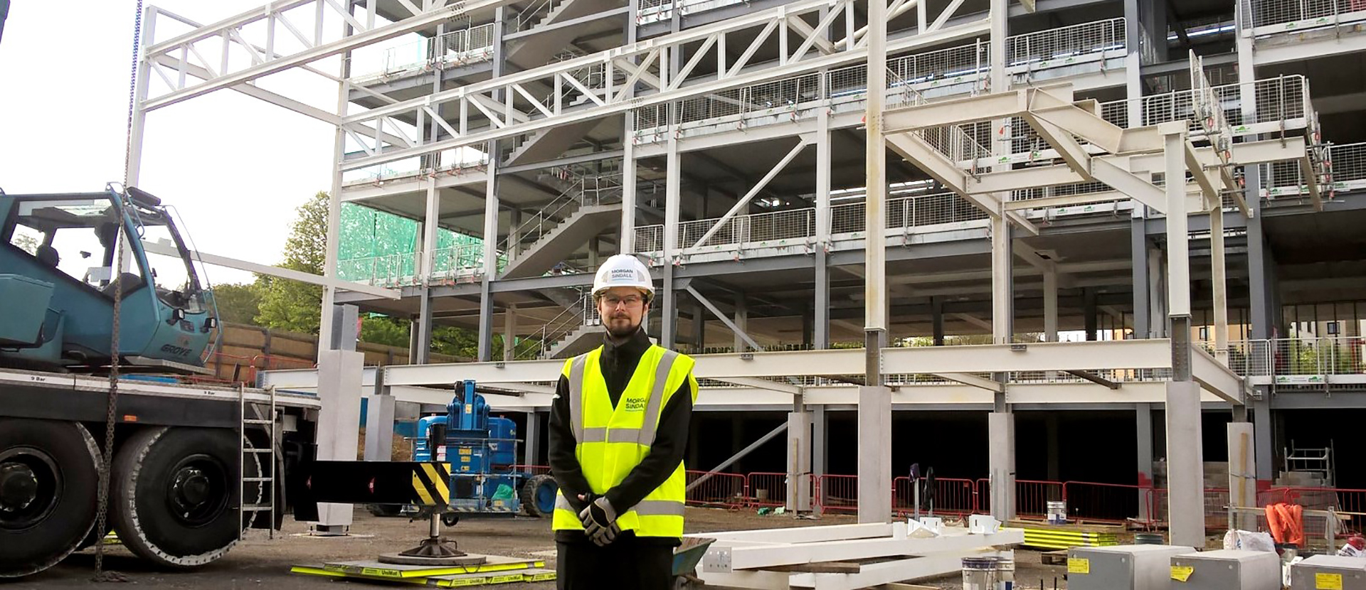 Construction management alumnus, Harry White standing in front of the new sports complex structure