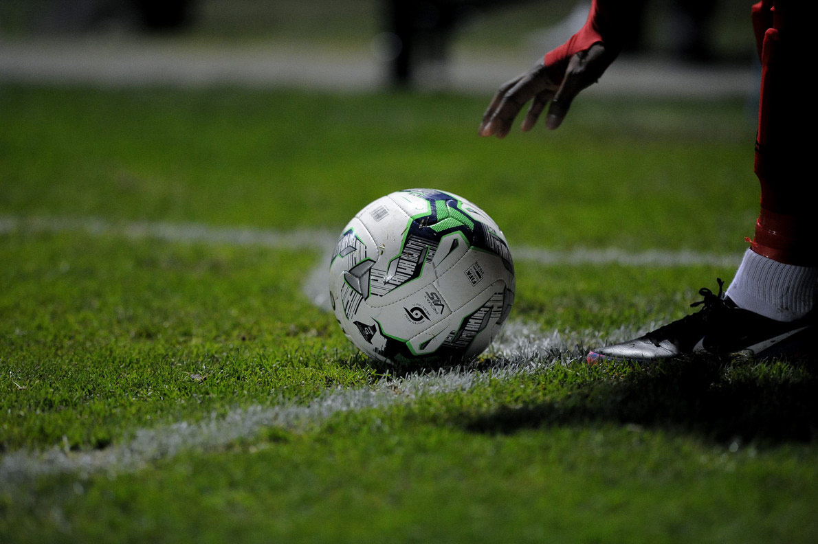 A player just about to pick up a football from the pitch