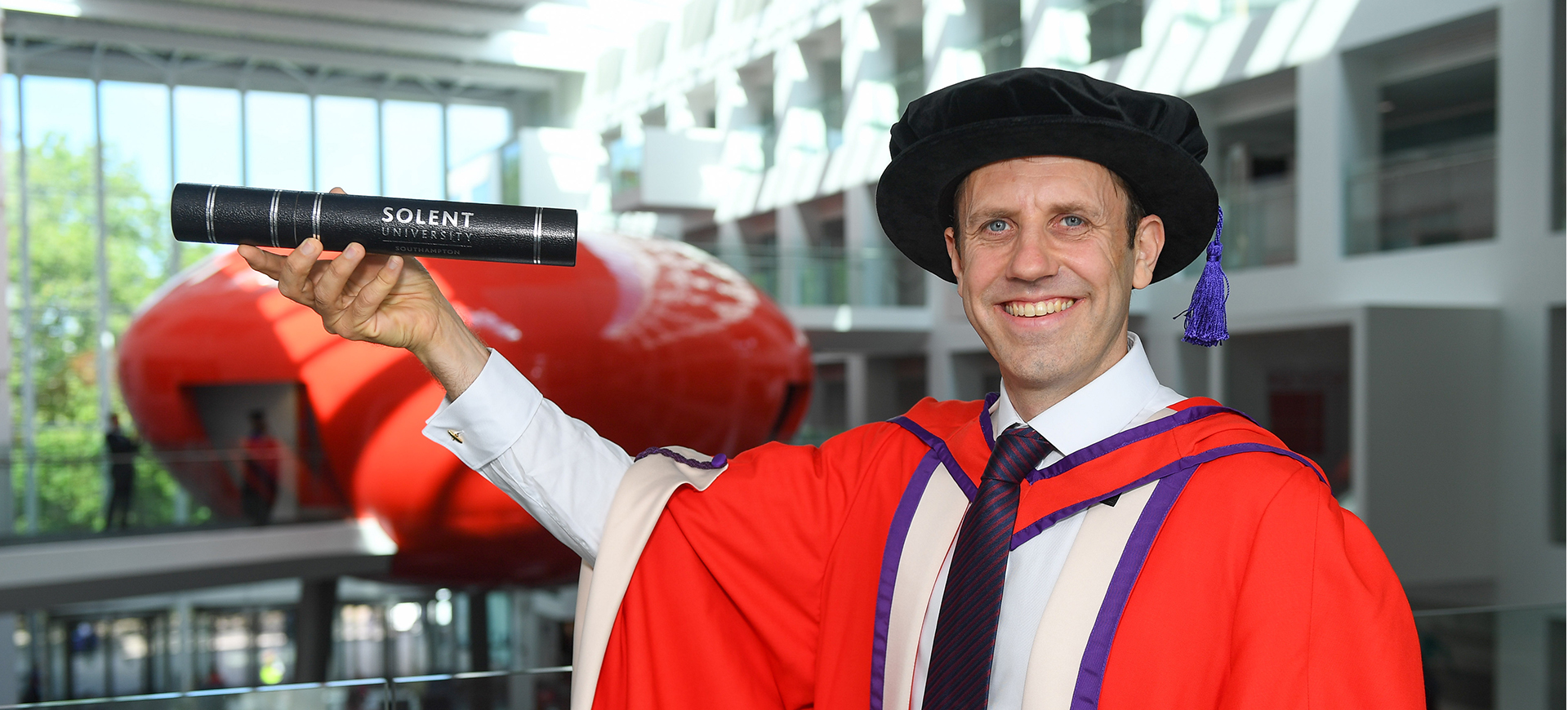 Oliver Ballhatchet MBE in the Spark building in graduation gown