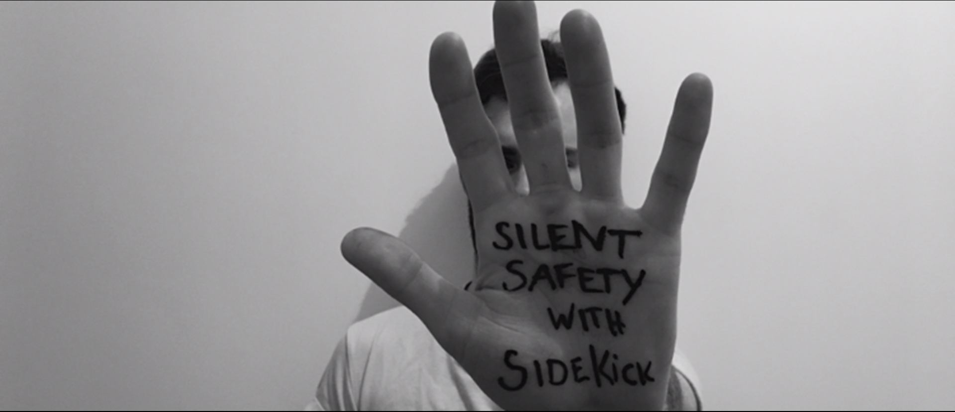 A person showing the palm of their hand with the words 'Silent safety with sidekick' written on it.