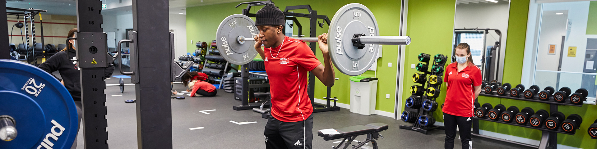 image of students lifting weights whilst being coached by another student