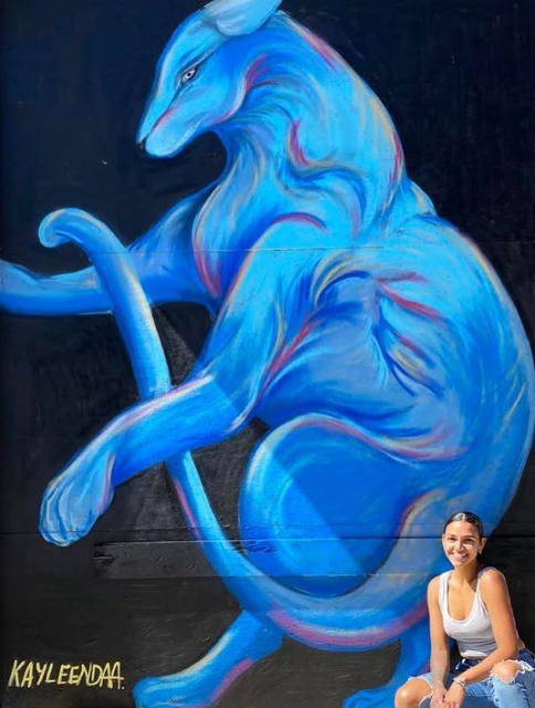 Picture of Kayleen in front of a mural she created