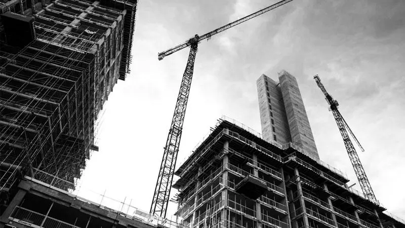High-rise buildings under construction with cranes in the background.