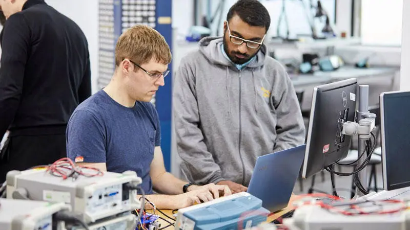 two male students in a computer workshop looking at a computer screen