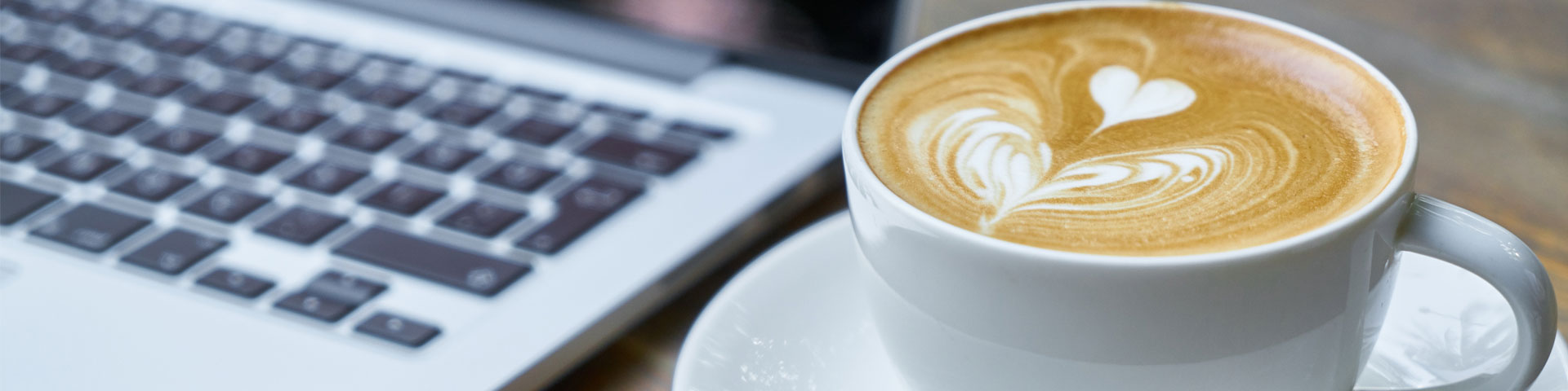 A latte next to an open laptop