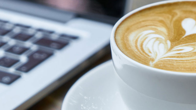 A latte next to an open laptop