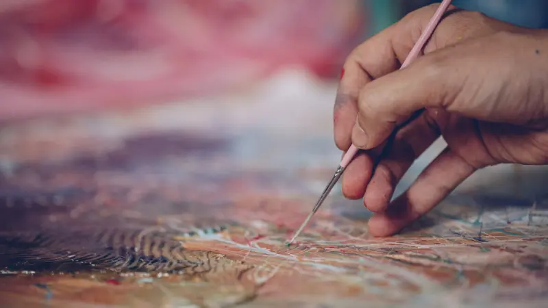 A hand painting onto a canvas