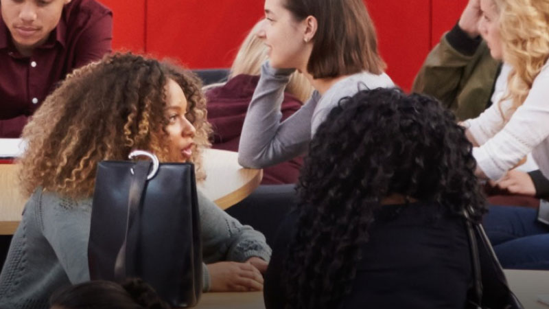 Students talking around tables on the Bridge