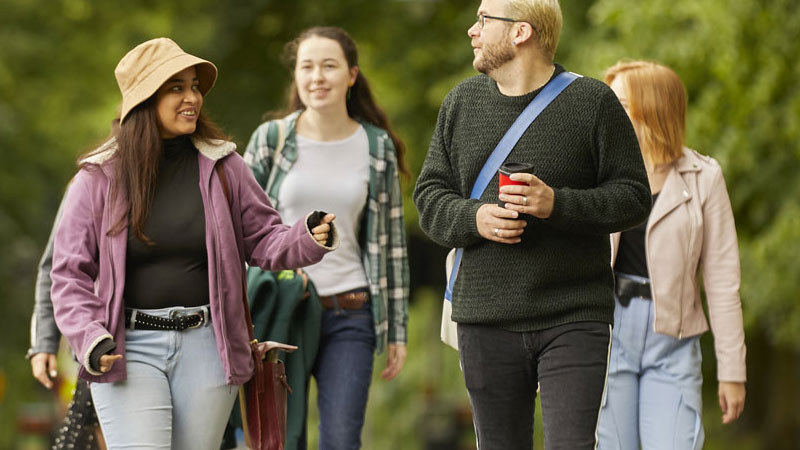 A group of four students walking through the park