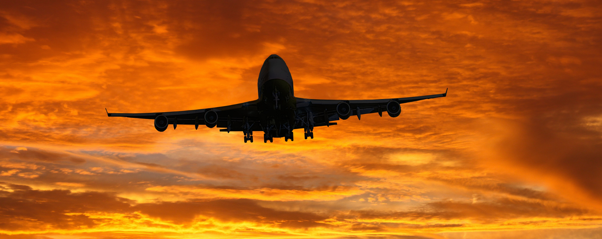 A plane in an orange cloudy sky.