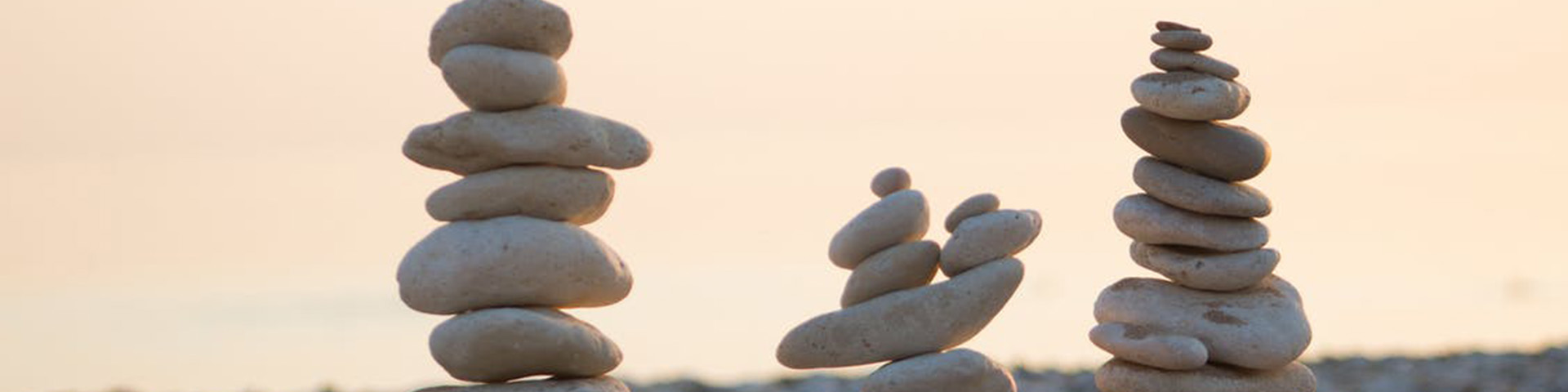 Three stacks of white or grey stones of varying heights and against a blurred background that looks like the sea.