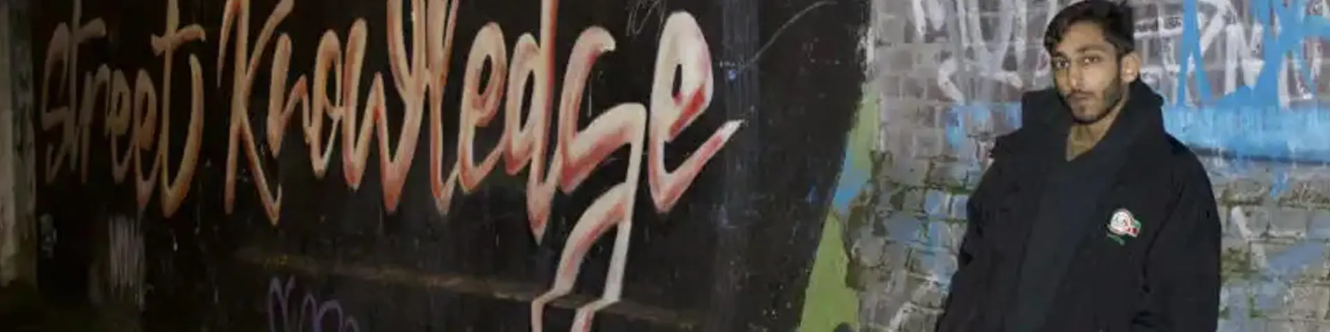 Avi against a wall with graffiti