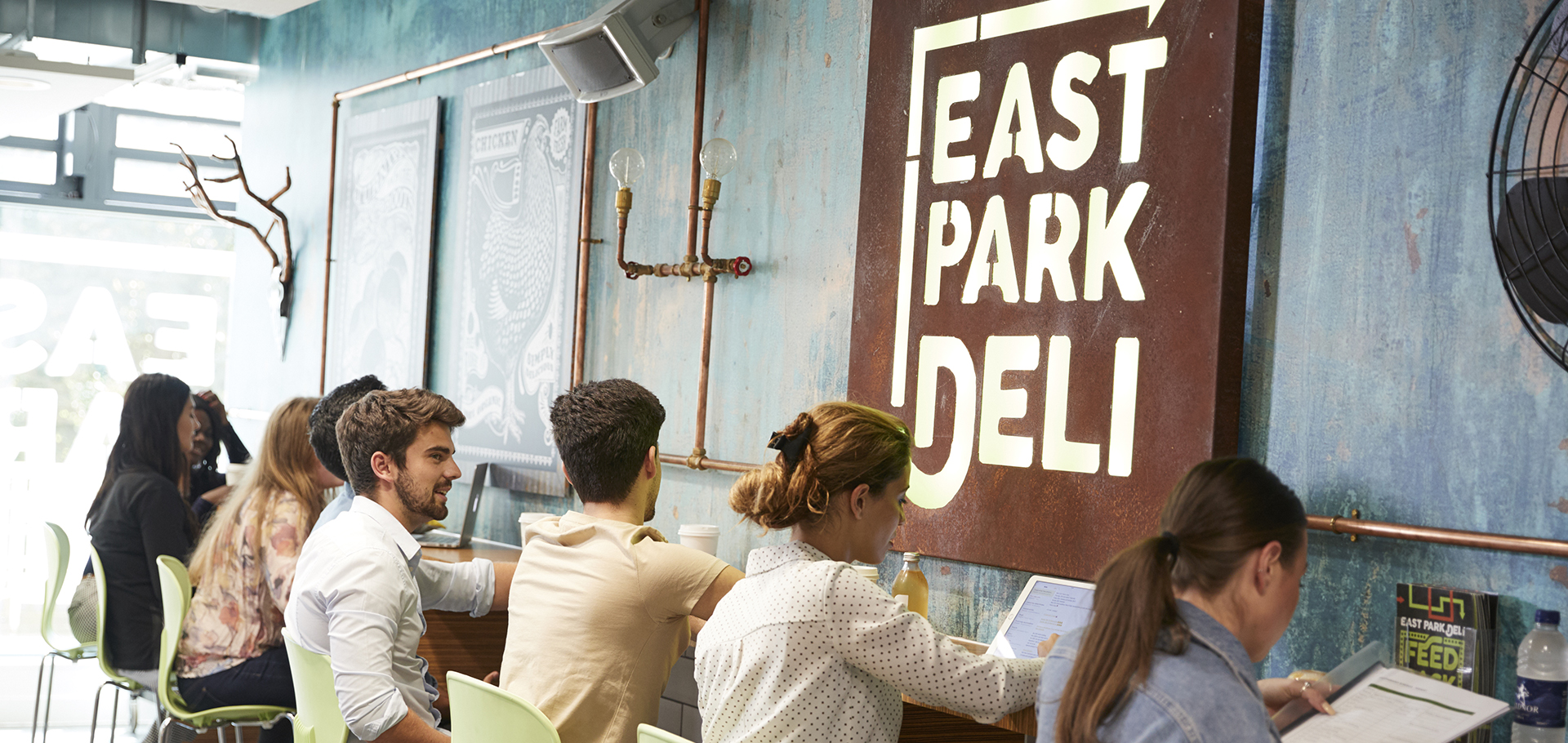Students sitting in front of an East Park Deli sign