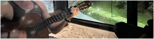 Luca Troiolo playing an acoustic guitar with a glimpse of the city in the background