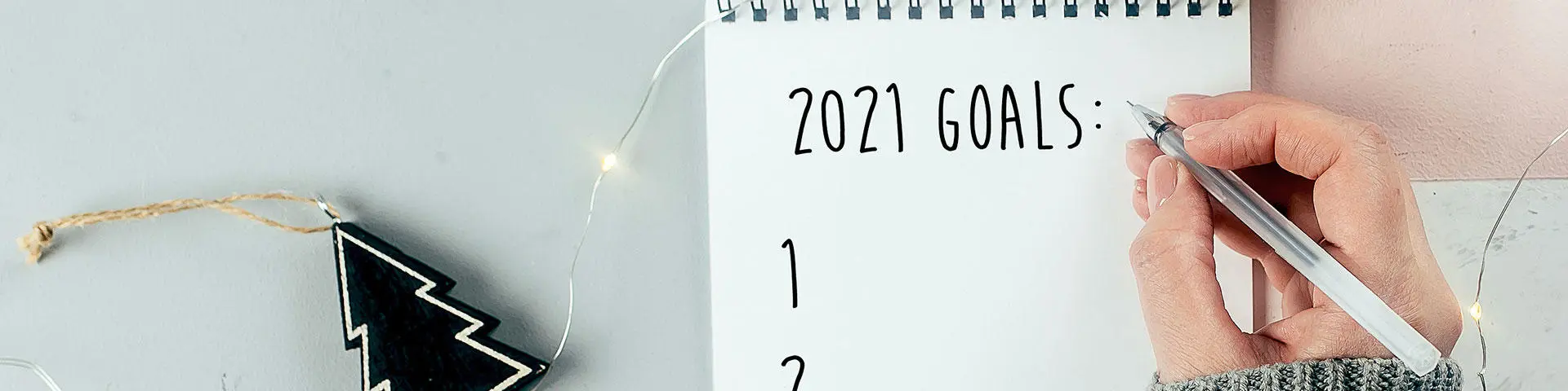 A person writing 2021 goals on a notepad
