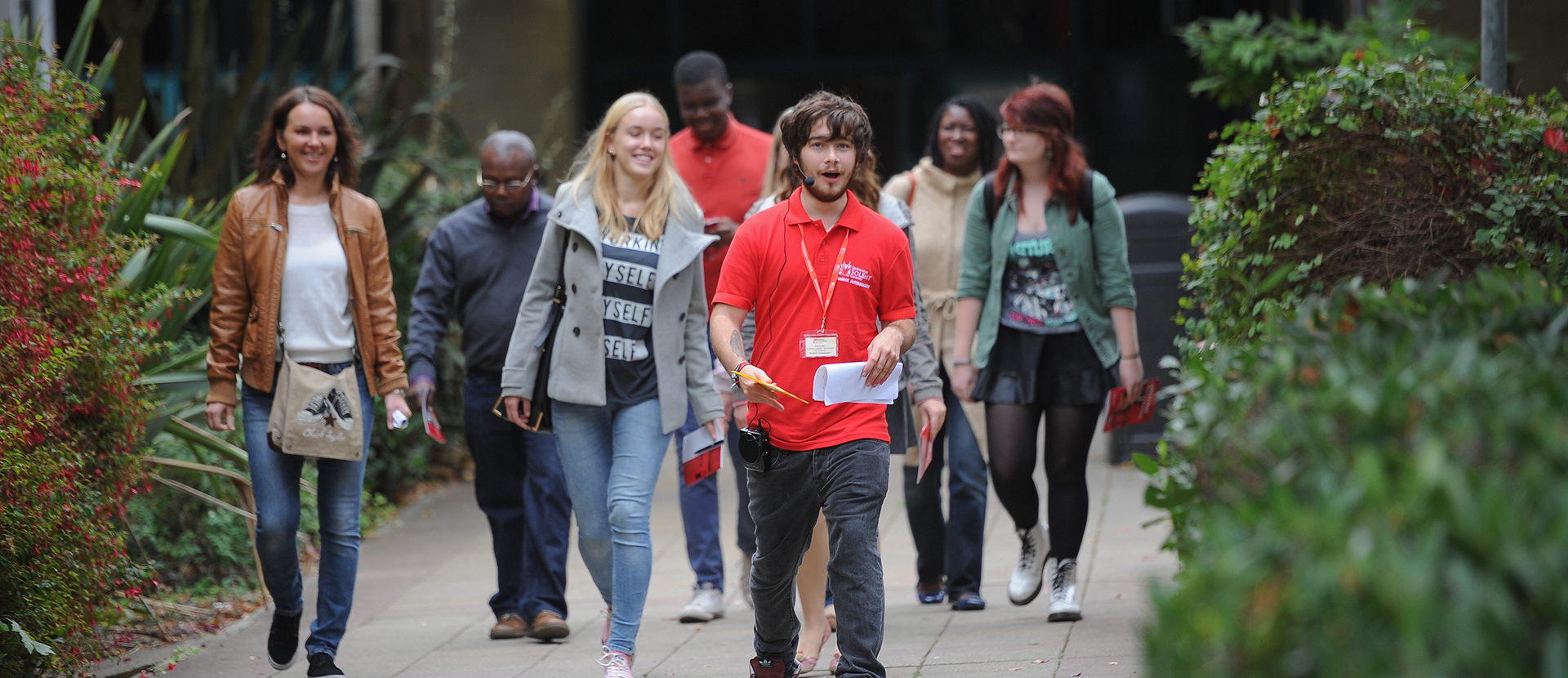 A group of people being led through the campus by a student ambassador in a red t-shirt