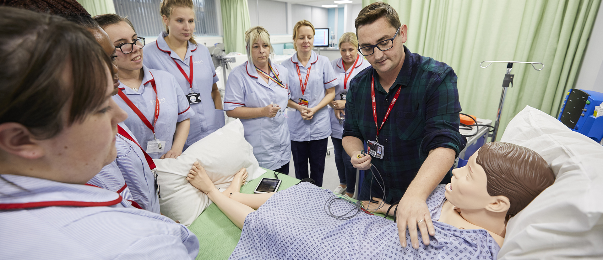 Nursing students examining a patient with their lecturer