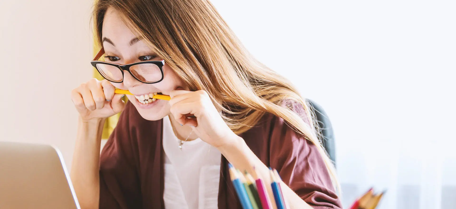 Someone chewing a pencil while working on a laptop