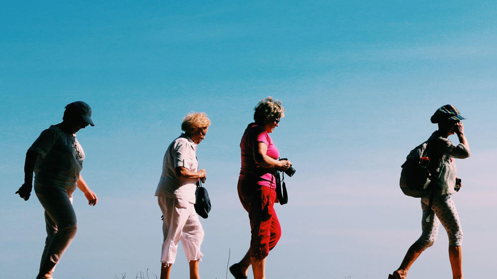 Four older women going for a walk in the sun