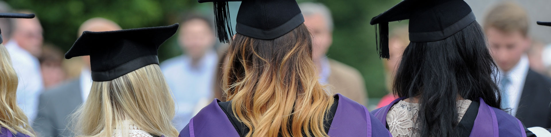 Shot of the backs of three female graduates wearing mortarboards and gowns.