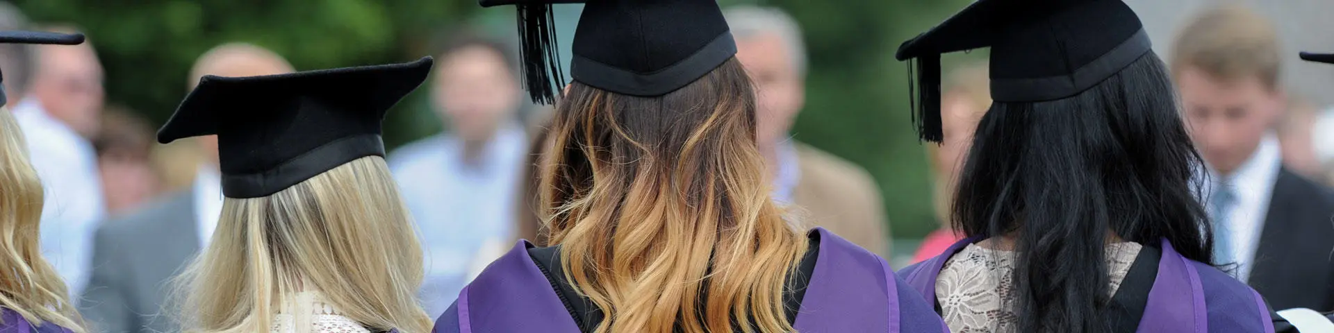 Three Solent University graduates in caps and gowns.
