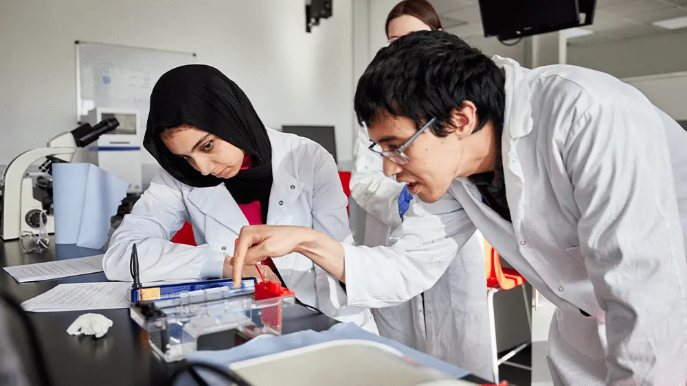 Two students with a lecturer in the biomedical science lab at Solent.