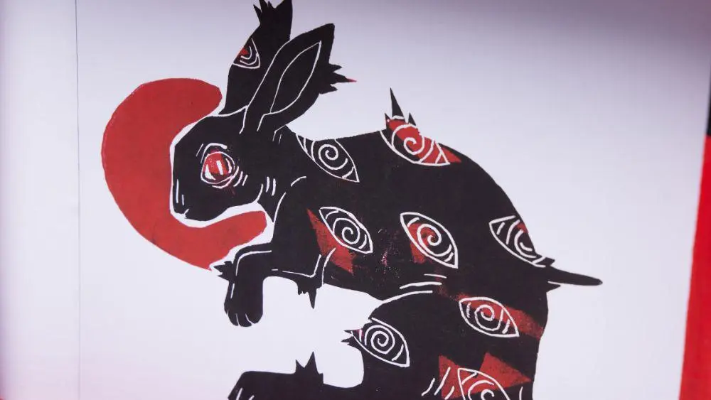 Close up of illustration of a black rabbit with multiple eyes.