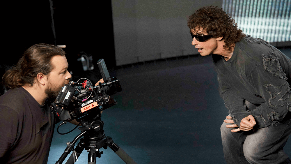 A photo of a graduate operating a camera as the lead singer of Don Broco sings into it.