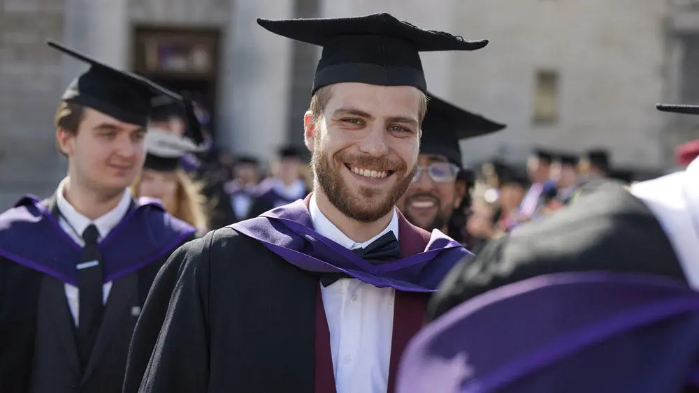 A Solent graduate wearing mortarboard and gown