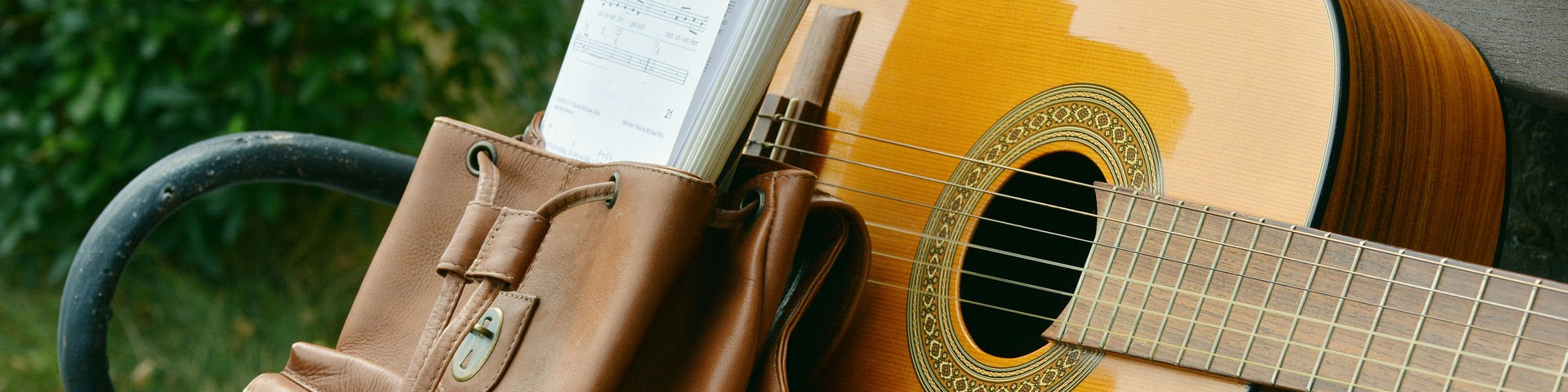 A guitar and a satchel on a bench