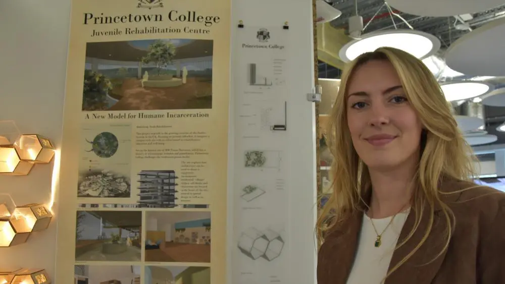 Harriet Rossall standing next to her poster work at the Summer Show