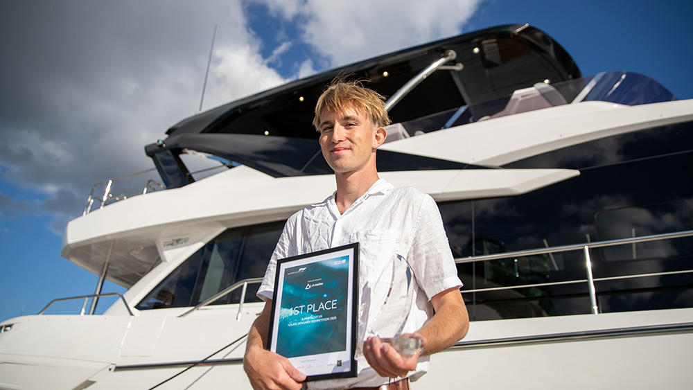 Jack Francis holding his award in front of a Superyacht at Southampton International Boat Show