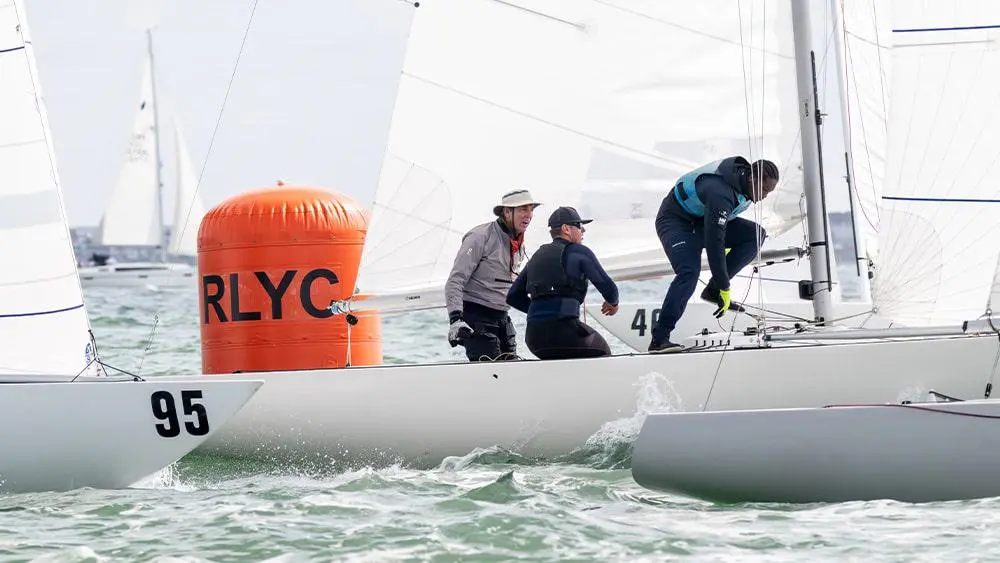 Three people on a sailing boat in the water.