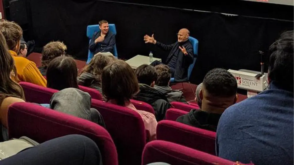 Students sat in a lecture theatre, with Mark Aldridge and Mark Gatiss sat talking at the front.