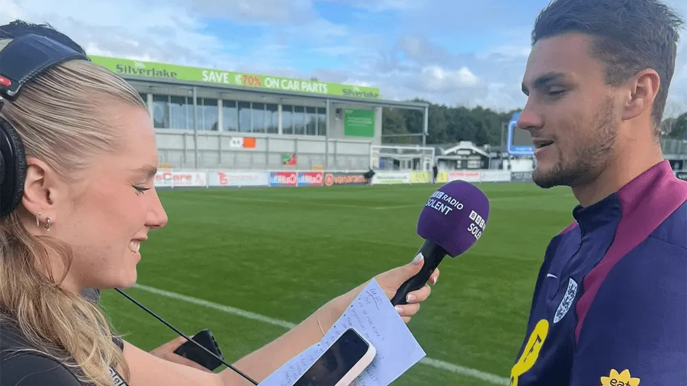 Millie Payne on a football pitch interviewing a sportsperson.