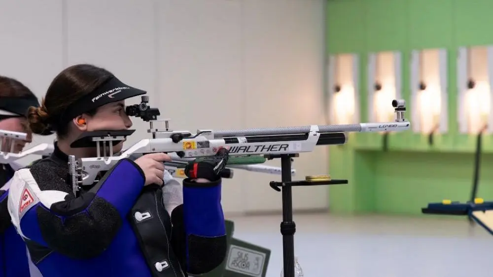 Sophie aiming an air rifle at a target in a competition