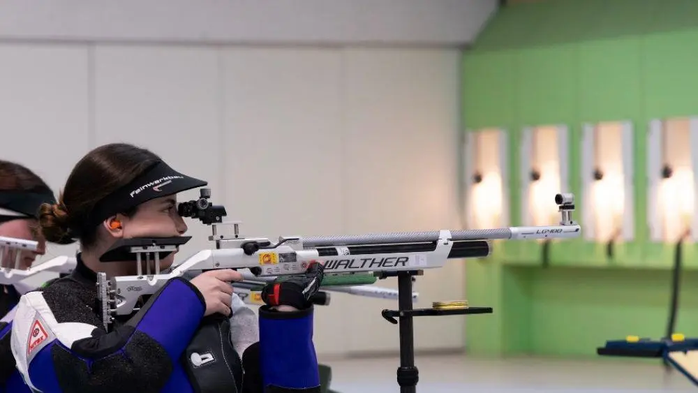 Sophie aiming an air rifle at a target in a competition