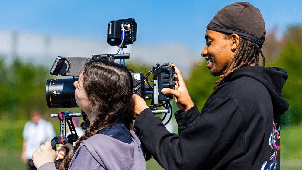 Rashaan Hersi operating a camera on location with a female student.