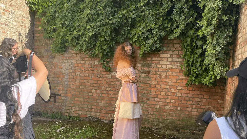 A model being photographed against a brick wall.