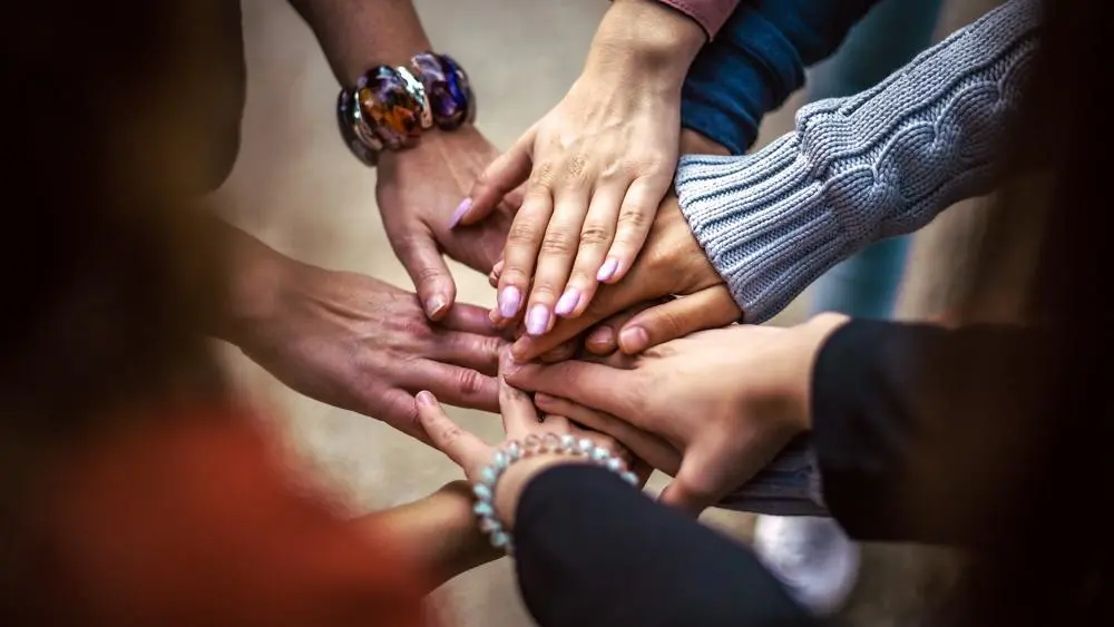 6 hands coming together in the middle signifying unity