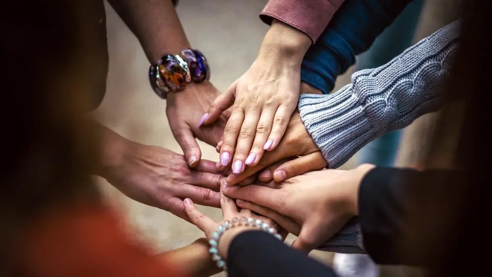 6 hands coming together in the middle signifying unity