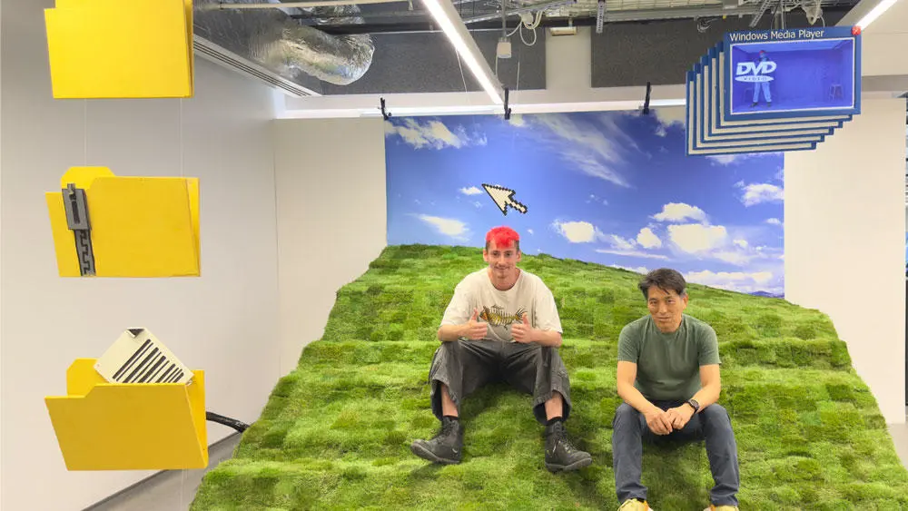 Owen and a staff member sat on the turf of the Microsoft Hill sculpture